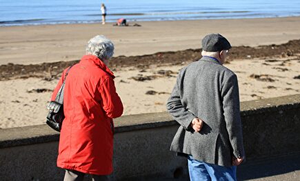 Una pareja de jubilados pasea junto a la playa | Alamy