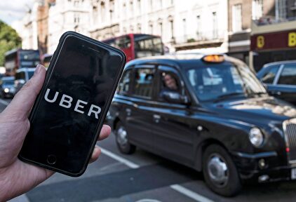 Un móvil con la app de Uber frente a un taxi tradicional en Londres | EFE