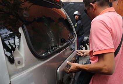 Un miembro del equipo de Guaidó comprueba el estado de la furgoneta tiroteada. | EFE
