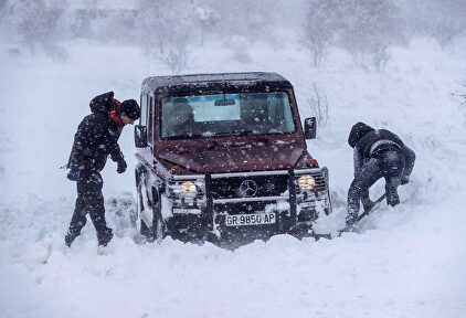 Dos hombres intentan sacar su todoterreno atrapado en la nieve este lunes en Yecla | EFE