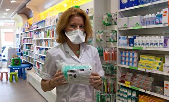 Una farmacéutica con mascarilla | Alamy