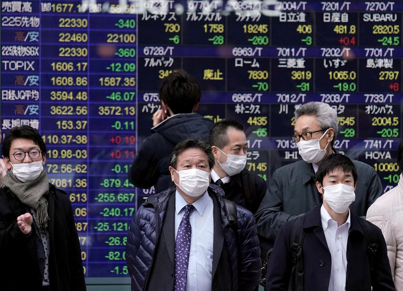 Varios viandantes pasan frente a una pantalla con información bursátil, este miércoles, en Tokio. | EFE