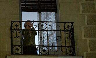 Una mujer aplaude a los sanitarios desde su balcón. | EFE