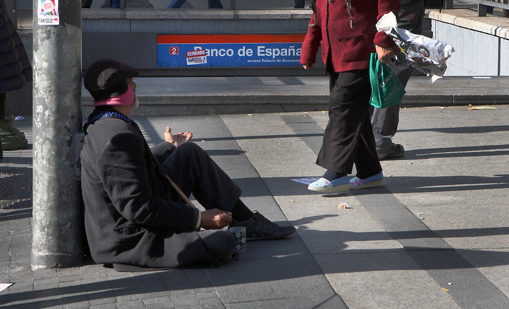 Un hombre pide limosna a la salida de la estación de metro Banco de España, en Madrid