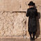 Un niño reza junto a la roca, vestido de una forma que lo identifica como judío ortodoxo