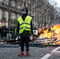 Un manifestante permanece parado y a su espalda se quema un amasijo de objetos que han sido arrancados del mobiliario urbano de París.