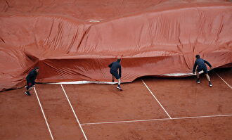 Varios voluntarios cubren la pista de tierra batida. |  EFE