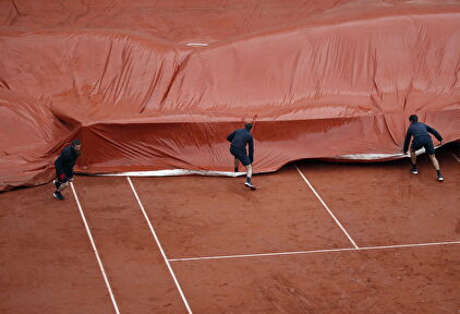Varios voluntarios cubren la pista de tierra batida. |  EFE