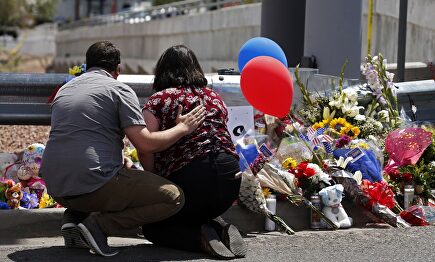 Personas dejen flores cerca al lugar del tiroteo. |  EFE