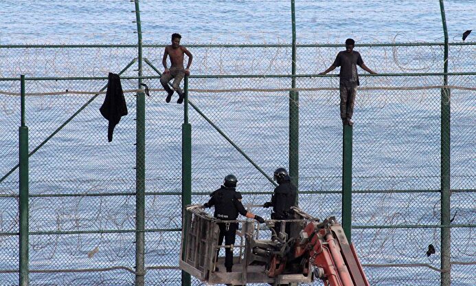 Dos inmigrantes subidos a la valla de Ceuta. | Archivo