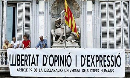 El cantante Lluis Llach, el exdiputado Antonio Baños y la actriz Silvia Bel colocan la nueva pancarta |  EFE EFE