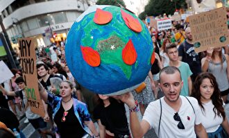 Un joven lleva globo terrestre en llamas durante la manifestación por la emergencia climática. |  EFE
