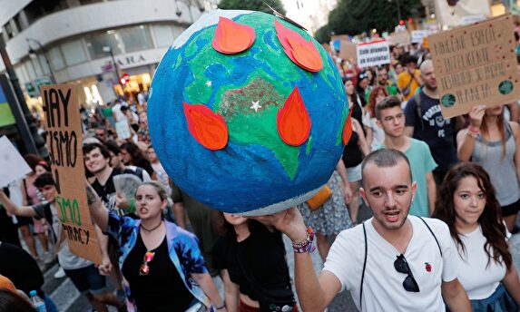 Un joven lleva globo terrestre en llamas durante la manifestación por la emergencia climática. |  EFE