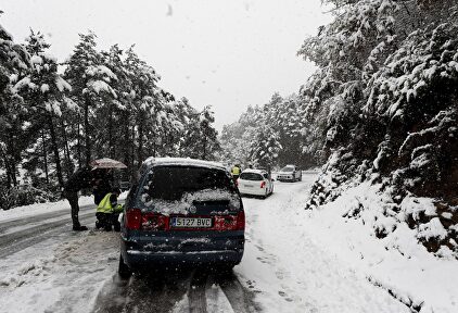 Efectivos de la Guardia Civil ayudan a varios conductores a colocar cadenas en sus vehículos en la N-135 en el Puerto de Erro, en Navarra |  EFE