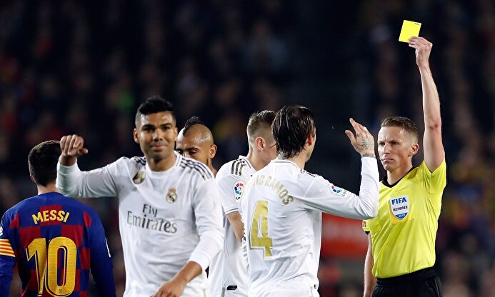 Hernández Hernández, el árbitro del Clásico Barcelona-Real Madrid, muestra la amarilla a Sergio Ramos. |  EFE