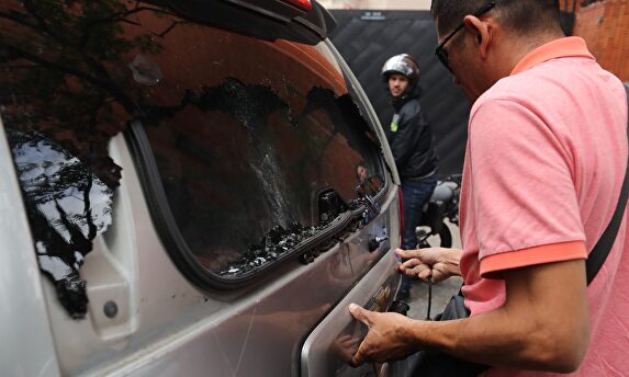 Un miembro del equipo de Guaidó comprueba el estado de la furgoneta tiroteada. |  EFE