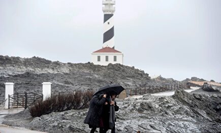 Dos personas caminan por las inmediaciones del faro de Faváritx, en el municipio de Mahón. |  EFE