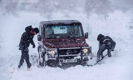 Dos hombres intentan sacar su todoterreno atrapado en la nieve este lunes en Yecla |  EFE
