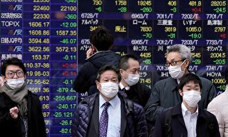 Varios viandantes pasan frente a una pantalla con información bursátil, este miércoles, en Tokio. |  EFE