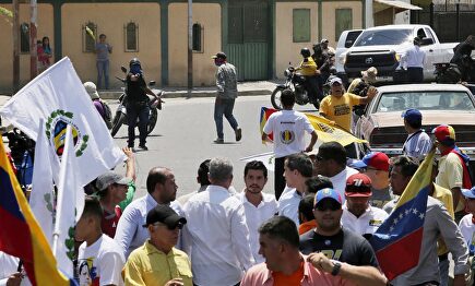 Un paramilitar encapuchado apunta con su arma a Guaidó. |  EFE
