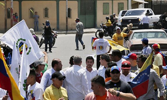 Un paramilitar encapuchado apunta con su arma a Guaidó. |  EFE