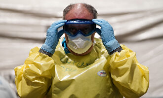 Un sanitario se coloca su traje de seguridad. | Comunidad de Madrid