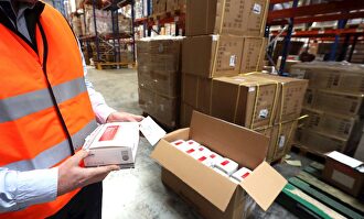 Un operario muestra los test rápidos recibidos. | EFE