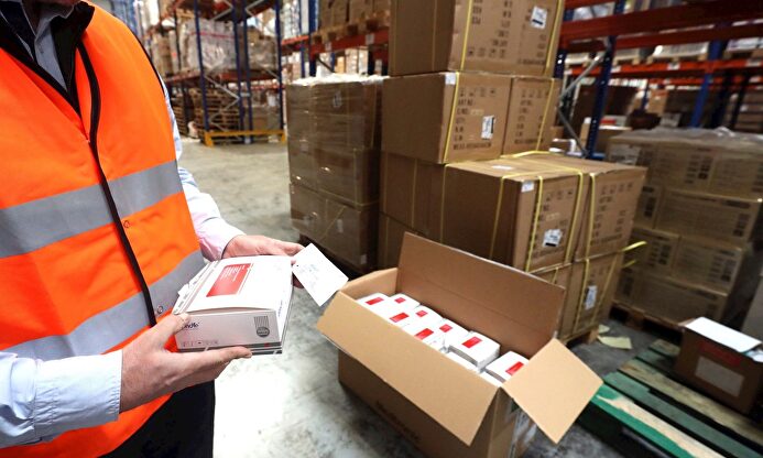 Un operario muestra los test rápidos recibidos. | EFE