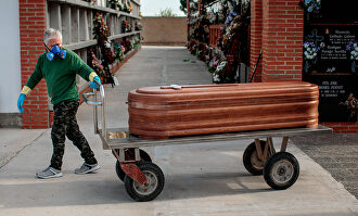 Un operario de un cementerio de Valencia traslada un féretro durante un entierro. | EFE