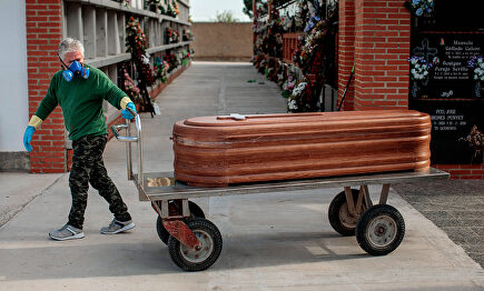 Un operario de un cementerio de Valencia traslada un féretro. | EFE