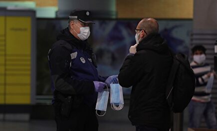 Un policía entrega a un hombre una mascarilla en la estación de Cercanías de Atocha. | EFE
