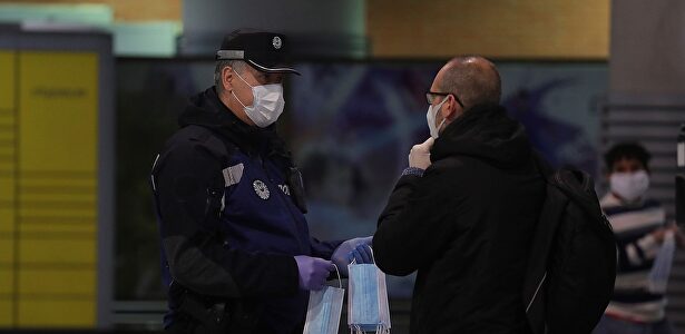 Un policía entrega a un hombre una mascarilla en la estación de Cercanías de Atocha. | EFE