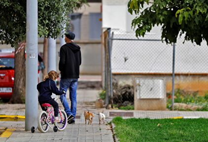 Un padre junto a su hija pasea a sus dos perros en la calle. | EFE