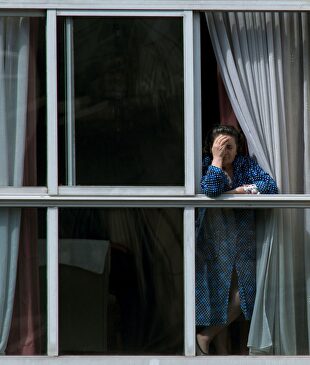 Una mujer asomada en la ventana de su vivienda en Orense. | EFE