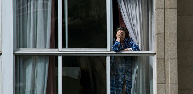 Una mujer asomada en la ventana de su vivienda en Orense. | EFE