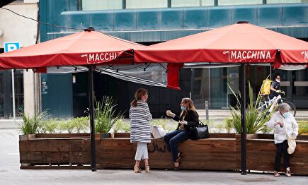 Varias personas toman café bajo las sombrillas de una terraza de una cafetería | EFE