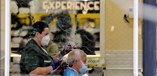 Una peluquera corta el pelo a un cliente protegidos ambos con mascarillas y guantes este sábado, en Valencia. | EFE