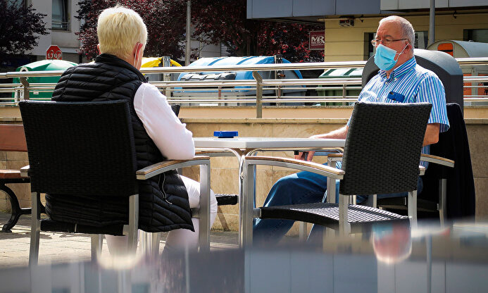 Dos personas en una terraza con mascarillas. | EFE