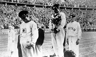 Sohn recibe la medalla de oro con la mirada al suelo y tapándose la bandera de Japón. | Archivo