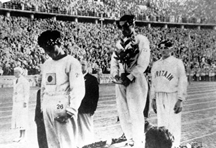 Sohn recibe la medalla de oro con la mirada al suelo y tapándose la bandera de Japón. | Archivo