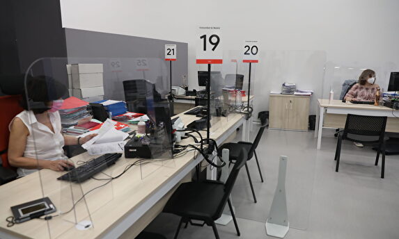 Dos trabajadoras de la Oficina del Empleador protegida con mascarilla y con una pantalla separador | Europa Press