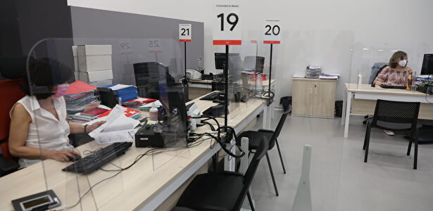 Dos trabajadoras de la Oficina del Empleador protegida con mascarilla y con una pantalla separador | Europa Press