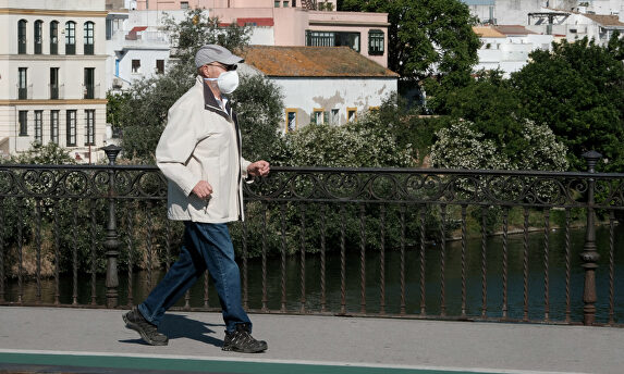 Una hombre mayor protegido con mascarilla pasea por el puente de Triana I Europa Press