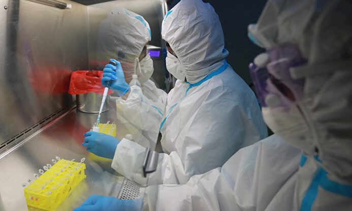 Dos sanitarios trabajan tapados con mascarilla y traje de protección contra el coronavirus en un laboratorio | EFE