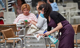 Una trabajadora desinfecta las mesas y sillas de una terraza de Pamplona | Europa Press