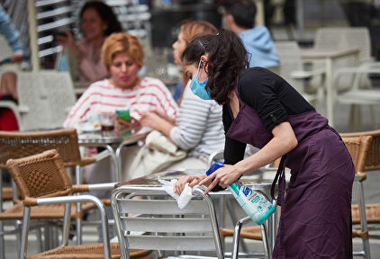 Una trabajadora desinfecta las mesas y sillas de una terraza. | Europa Press