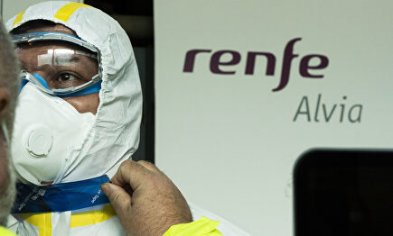 Un trabajador sanitario termina de colocarse su traje de protección junto a un tren Alvia | Mitma