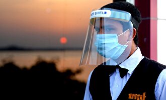 Un camarero con pantalla de protección y mascarilla. | EFE