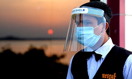 Un camarero con pantalla de protección y mascarilla. | EFE