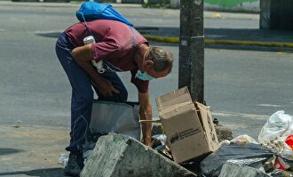Un hombre buscando comida en la basura en Venezuela | Alamy